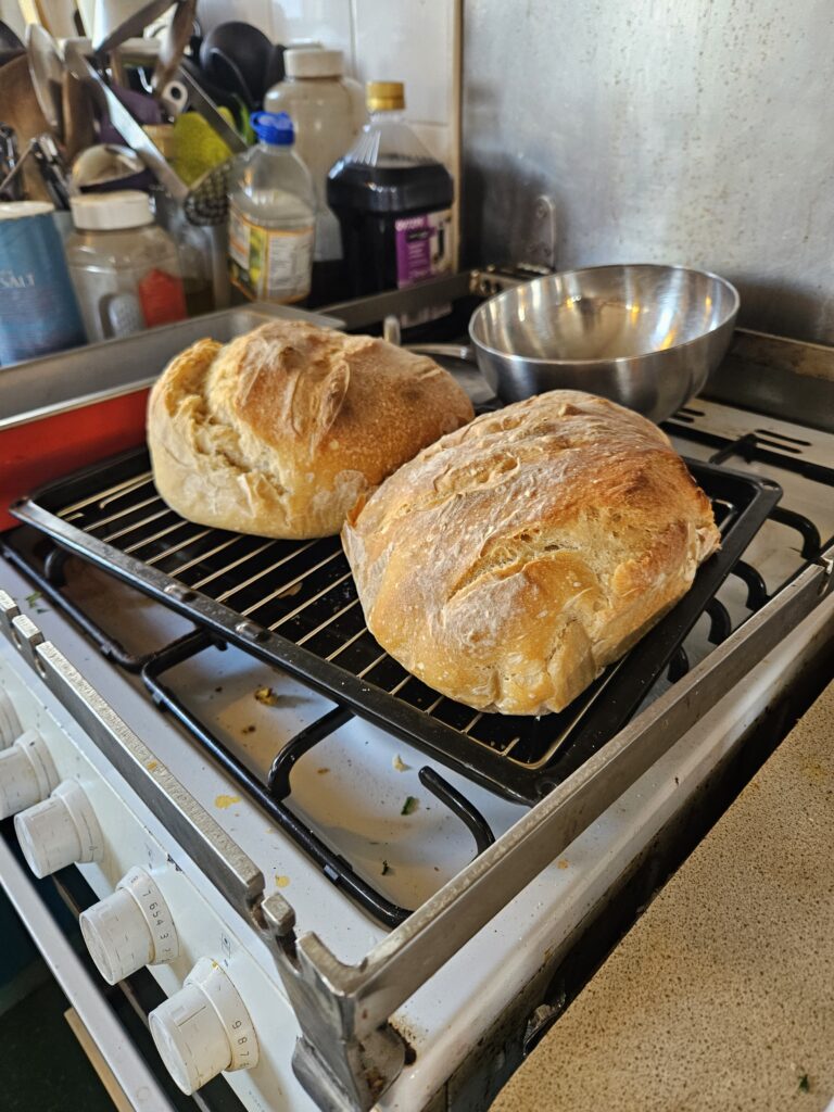 2 loaves of bread cooling on stovetop.