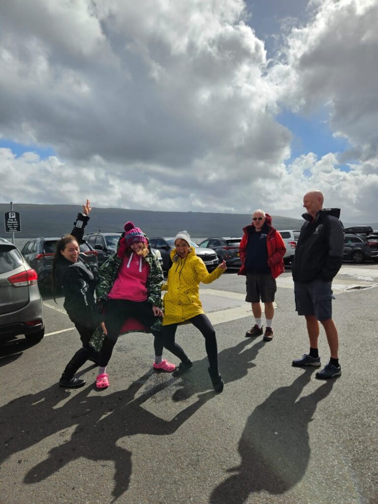 3 female divers dancing in car park while 2 male divers look on